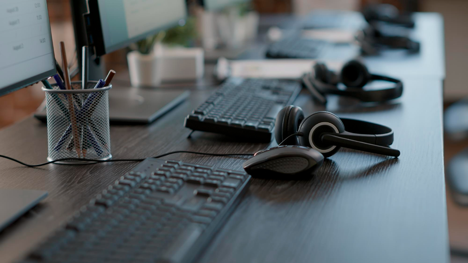 Image showing audio headsets used by call center agents to assist clients in telecommunication, alongside modern gadgets and computers at an empty customer service workstation